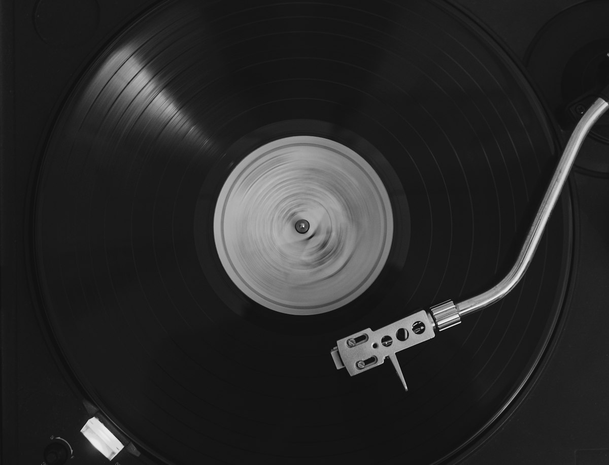 A vinyl record spinning on a turntable with a silver tonearm